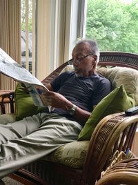 Man reading newspaper while sitting on seat at home