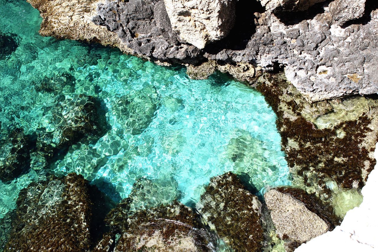 HIGH ANGLE VIEW OF ROCKS BY SEA