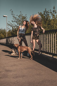 Women tossing hair while standing by dogs on footbridge