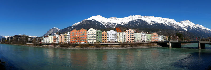 Buildings by lake against blue sky