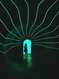 Silhouette man standing in illuminated tunnel