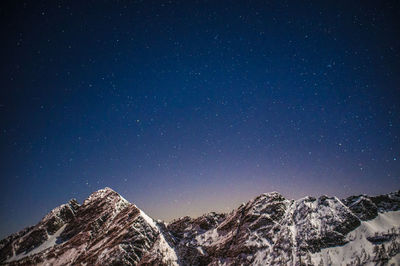 Scenic view of snowcapped mountains against sky at night