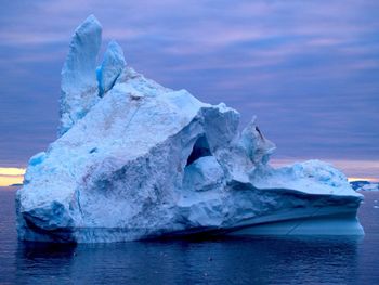 Iceberg in lake against sky during sunset