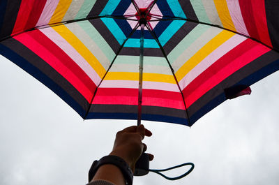 Low angle view of person holding umbrella against sky