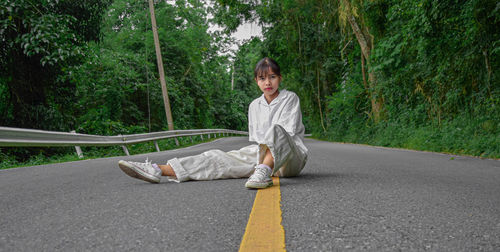 Portrait of a smiling young woman sitting on road