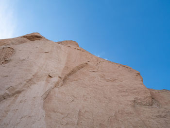 Low angle view of desert against clear blue sky