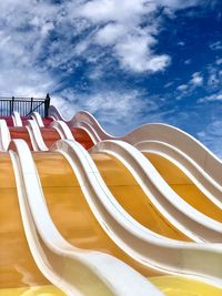 Low angle view of empty deck chairs against sky