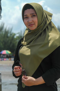 Portrait of young woman standing against sky