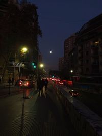 Illuminated street amidst buildings in city at night