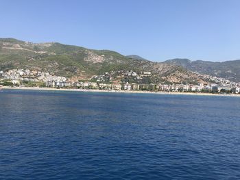 Scenic view of sea and townscape against clear blue sky