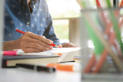 Midsection of woman reading book on table