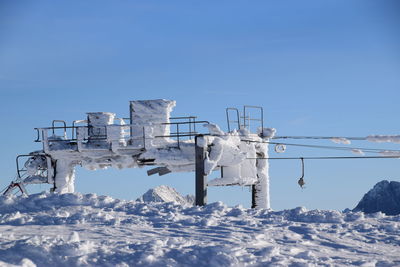 Low angle view of snow covered built structure against clear blue sky