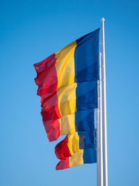 Low angle view of flag against clear blue sky