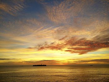 Scenic view of sea against dramatic sky during sunset