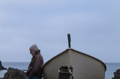 Adult man in leather jacket with a boat against sea and sky. almeria, spain