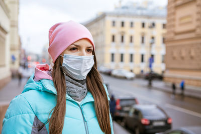 Cute woman in a medical mask walks the city streets in autumn