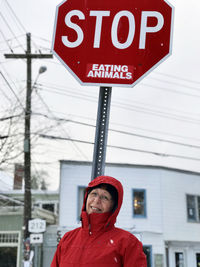 Portrait of smiling woman standing against stop sign