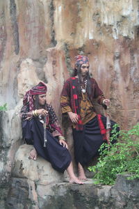Men in traditional clothing against wall