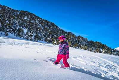 Girl standing in deep snow with mountains and forest in a background, andorra