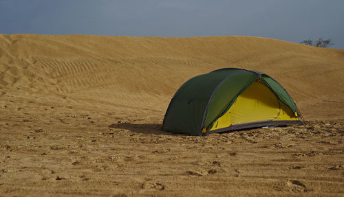 Tent on sand dune in desert against sky