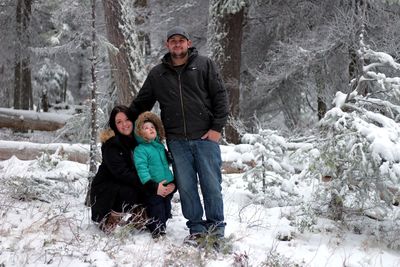 Portrait of parents with daughter in forest during winter