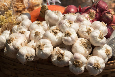 Close-up of garlic bulbs for sale in basket at market stall during sunny day