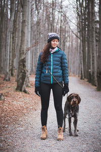 Full length of woman with dog in forest