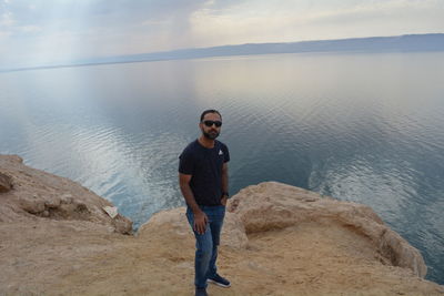 Full length of young man looking at sea against sky