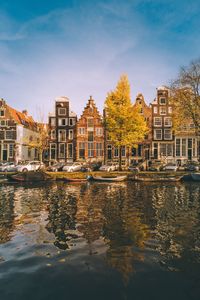 Canal by buildings against sky in city