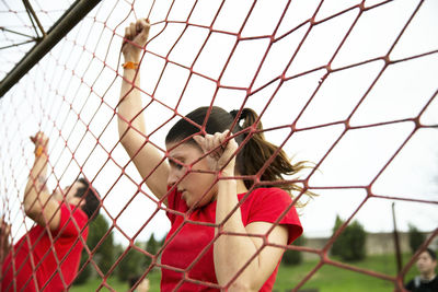 Low angle view of woman climbing netting during race