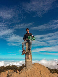 Low angle view of young man standing on rock