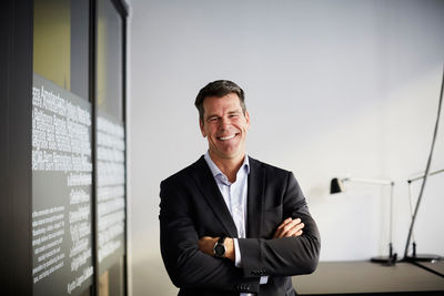 Portrait of confident mature businessman standing with arms crossed in office