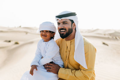 Father and son enjoying while kneeling in desert
