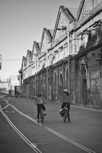 People riding bicycle in city against sky