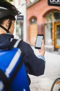 Cropped image of food delivery woman using map on smart phone in city