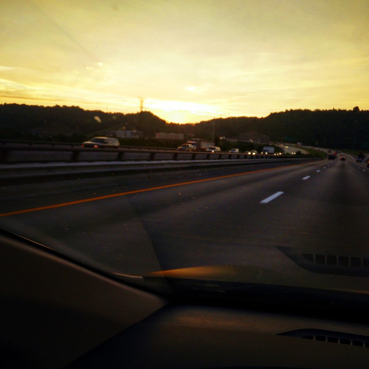 CAR ON ROAD AGAINST SUNSET SKY