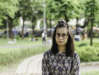 Portrait of young woman standing against trees