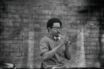 Portrait of street musician playing flute against brick wall