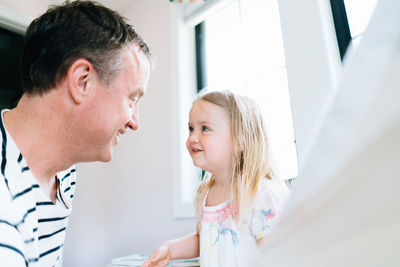 Cropped view of a father and daughter smiling at each other indoors