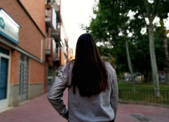 Rear view of woman standing against building