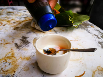 Half boiled eggs with soy sauce and pepper served in a cup on a stained table.