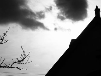 Low angle view of silhouette building against cloudy sky