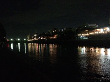 Illuminated bridge over river at night