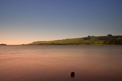 Scenic view of lake against clear sky at sunset