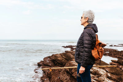 Full length of man on rock at beach against sky