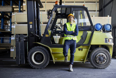 Portrait of confident worker at forklift in factory