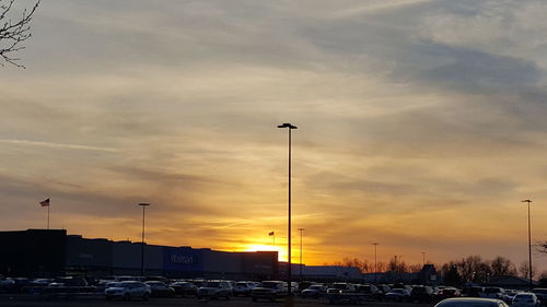 Cars on illuminated street against sky during sunset