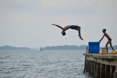 Full length of boy diving in sea against sky