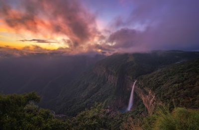 Scenic view of waterfall on mountain against sky during sunset