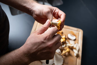 Cropped hand of man cutting mushrooms
